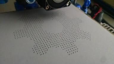 Photo of Pen Plotter plotting dashes in the shape of the open hardware logo